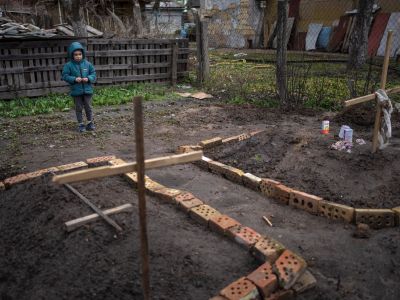 Шестилетний мальчик смотрит на могилу своей матери, умершей от голода, во дворе их дома в Буче. Фото: Rodrigo Abd / AP