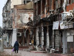 Местная жительница проходит мимо разрушенных зданий в Изюме Харьковской области, 25 ноября 2022 год. Фото: Анатолий Степанов/AFP/Getty Images